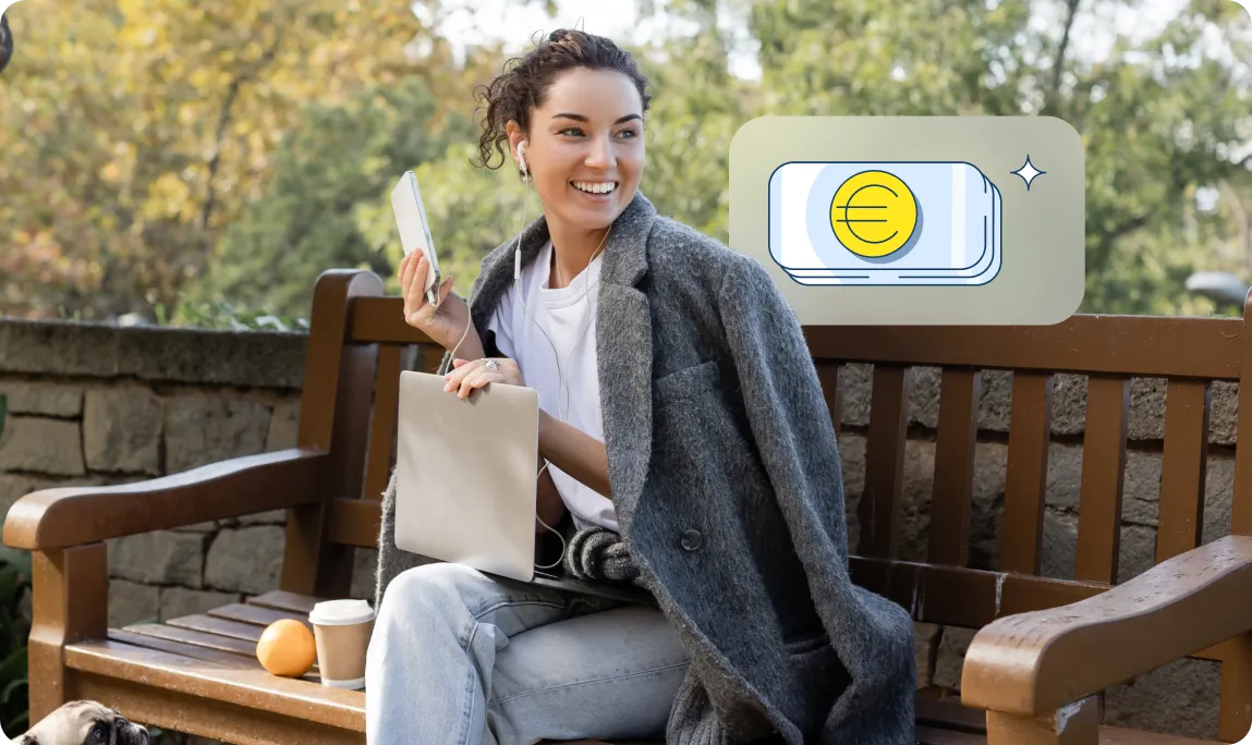 Eine junge Frau sitzt mit Laptop auf einer Parkbank, während die finanzblick App ein Symbol für Bargeld anzeigt.