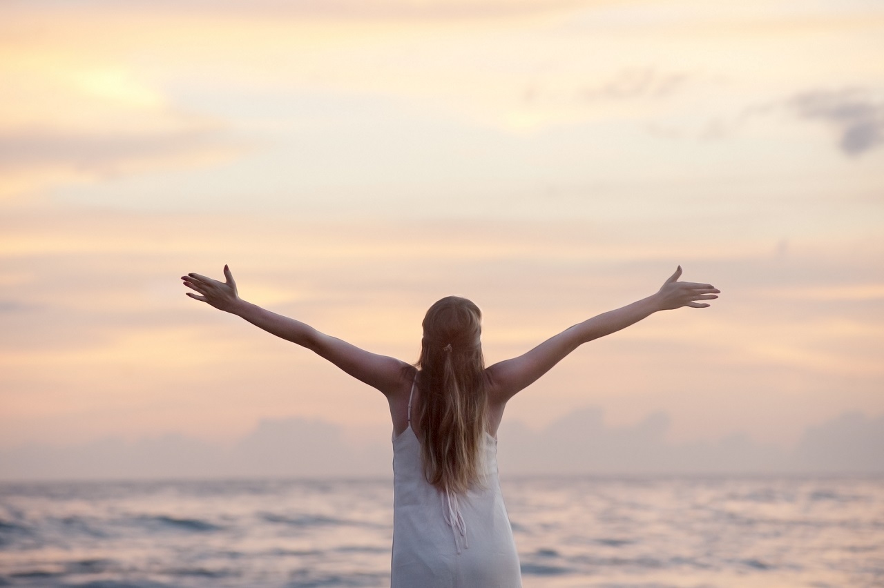 7 Gründe, warum mich ehrenamtliches Engagement so glücklich macht. Zu sehen: Eine Frau vor dem Horizont, die die Arme weit ausstreckt.
