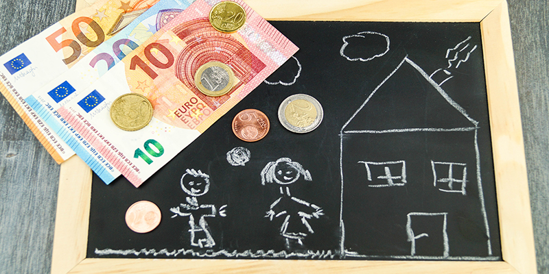 Auf einer Tafel wurden zwei Kinder skizziert. Darüber befindet sich ein zehn Euro Schein und Münzgeld