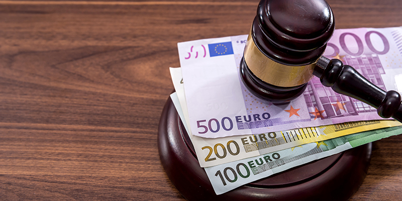 Der Richterhammer in Aktion. Euro Scheine liegen auf dem Tisch.